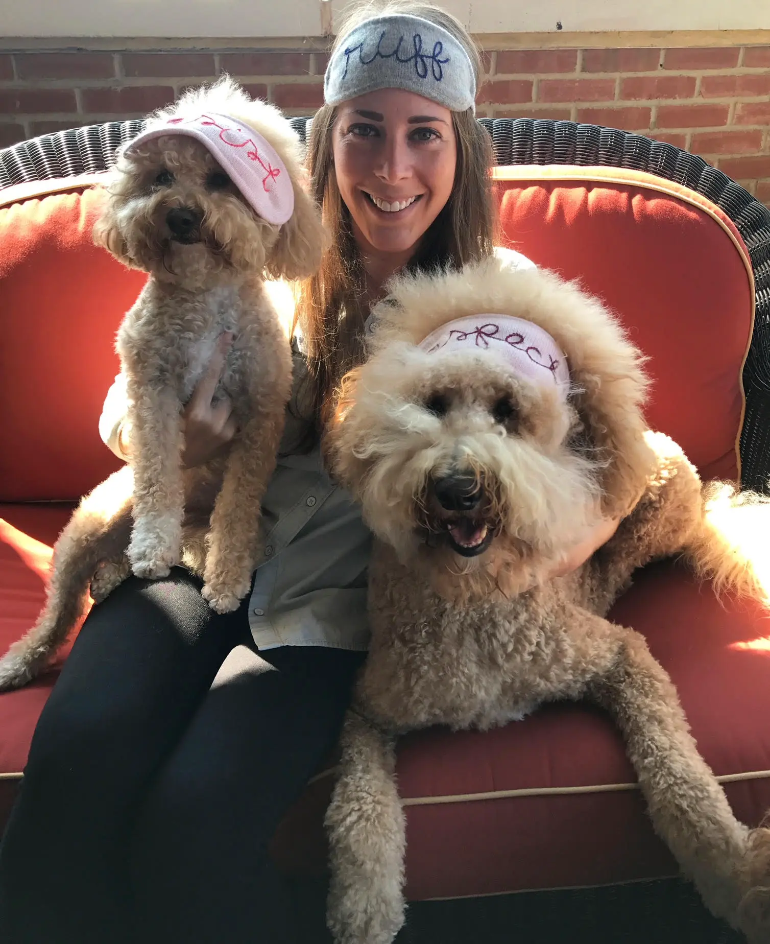 Paige with Sawyer and Charlie, both doodles wearing sleep masks, on a red patio couch
