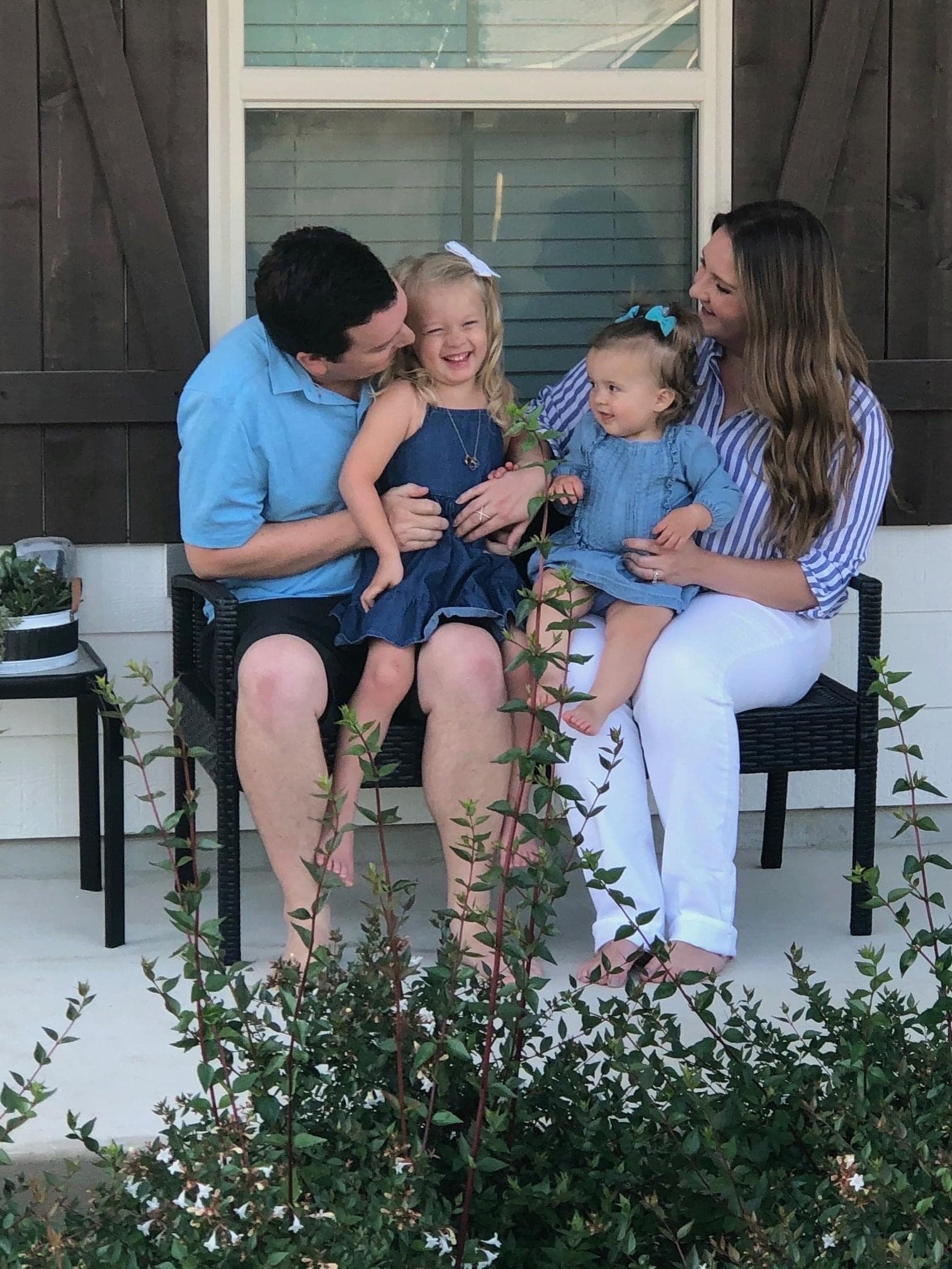 Joe and his wife on a porch with their two young daughters on their laps