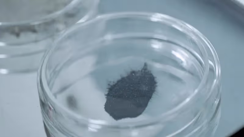 A pinch of dark carbon powder in a glass dish.