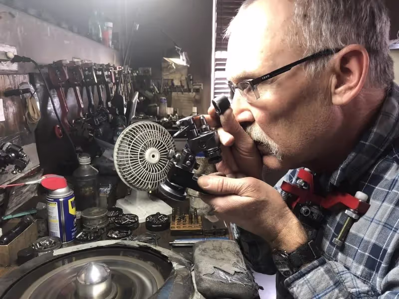 A master cutter inspecting a diamond through a loupe at his bench.