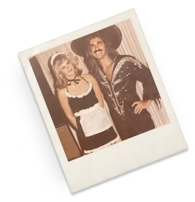 A polaroid of a woman in costume standing beside a man in an embellished jacket and wide-brimmed hat.