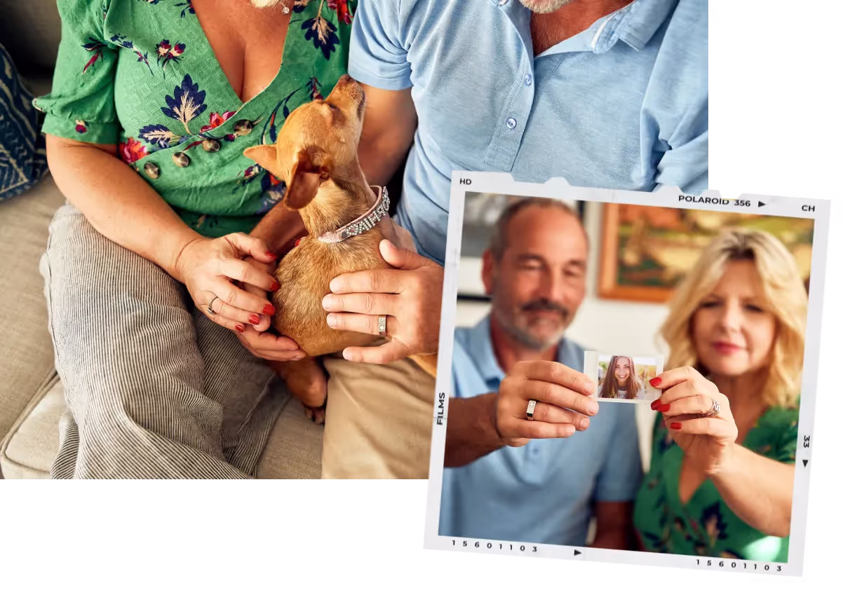 A couple sitting close together on a sofa, holding a small dog and a photograph of a young woman.