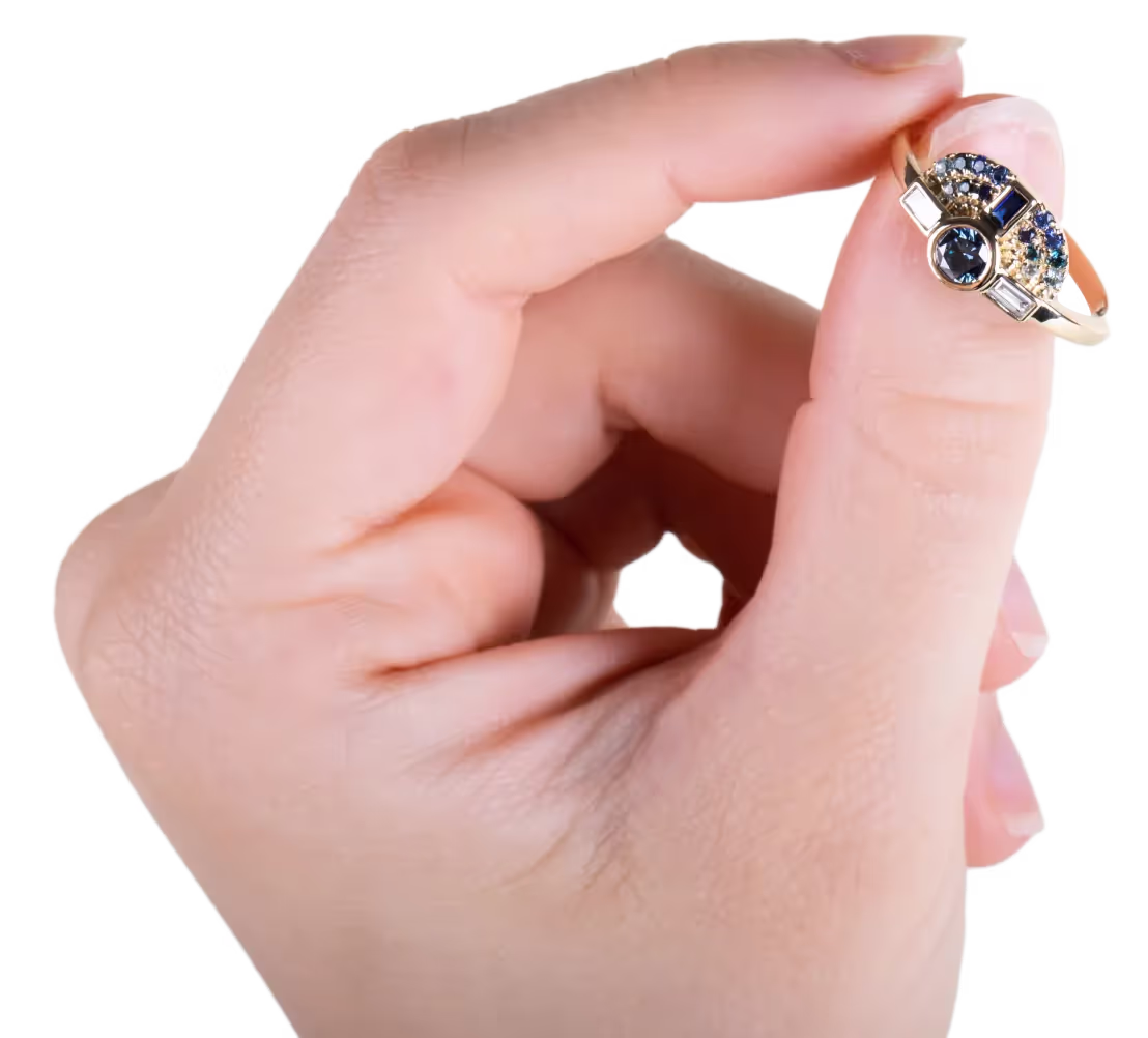 A hand holding a gold ring set with blue, white and clear gemstones.
