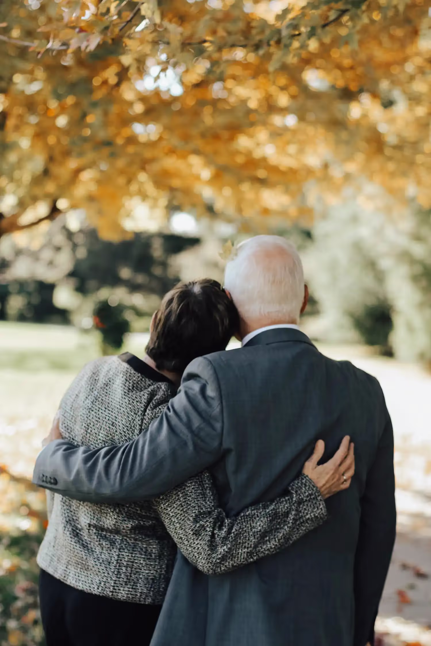 Elderly couple holding each other on a walk in autumn.
