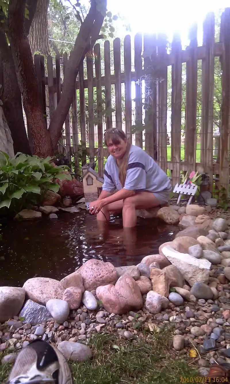 Joyce dipping her feet in her fish pond.