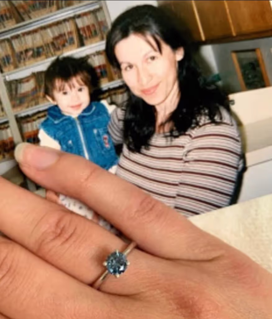 Person wearing a blue diamond ring holding photo of their daughter.