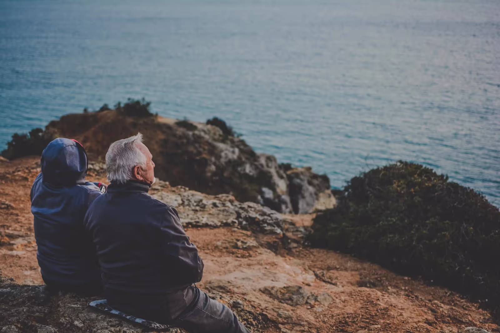 An elderly couple looking out at the ocean.