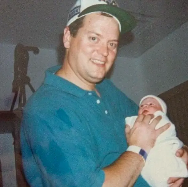 Rudy, as a younger man, cradles a newborn baby.