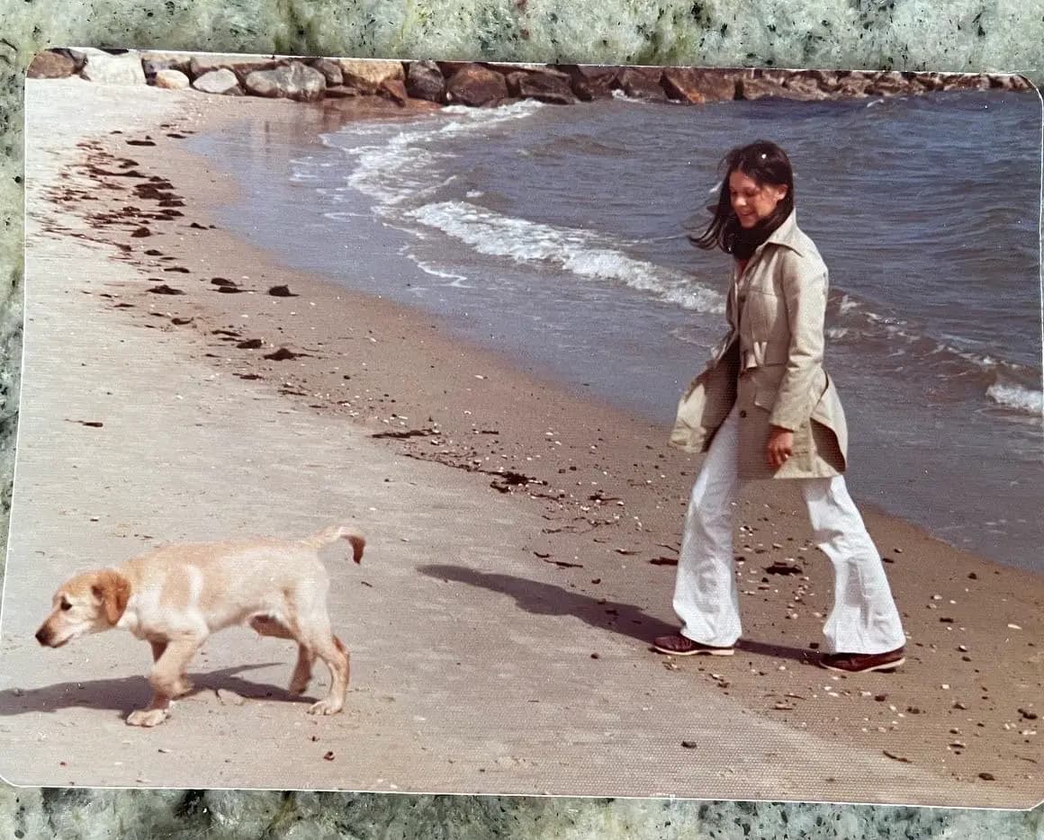 Vintage photo of Lizzie's mom walking along a beach with a puppy, one of the photos Lizzie is recreating.