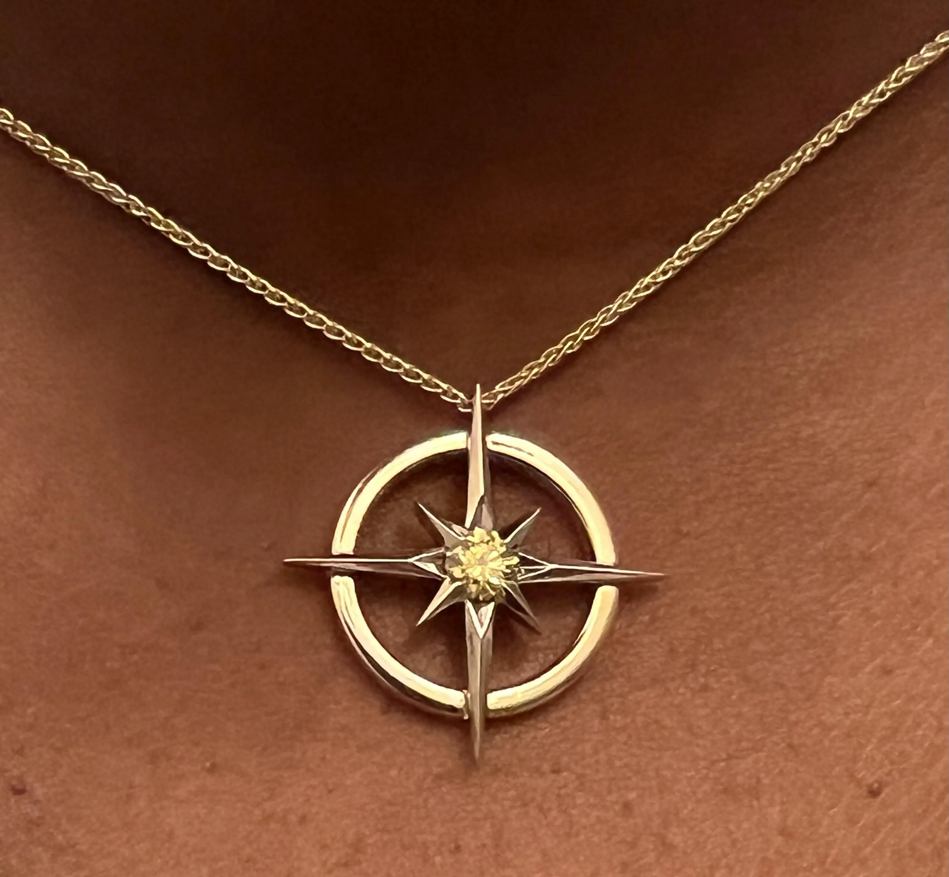 Gold compass-star pendant set with Orion’s yellow memorial diamond.