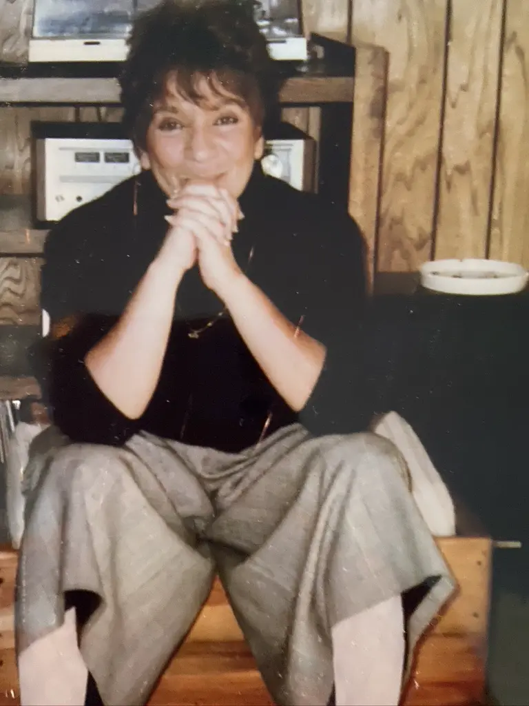 Vintage photo of Grandma Josephine sitting with her hands clasped, smiling.