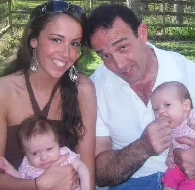 The author’s dad and a young woman smiling, each holding a baby.