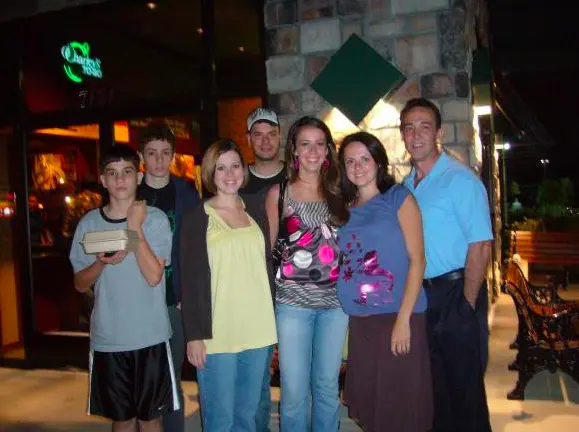 Family members standing together outside a restaurant at night.