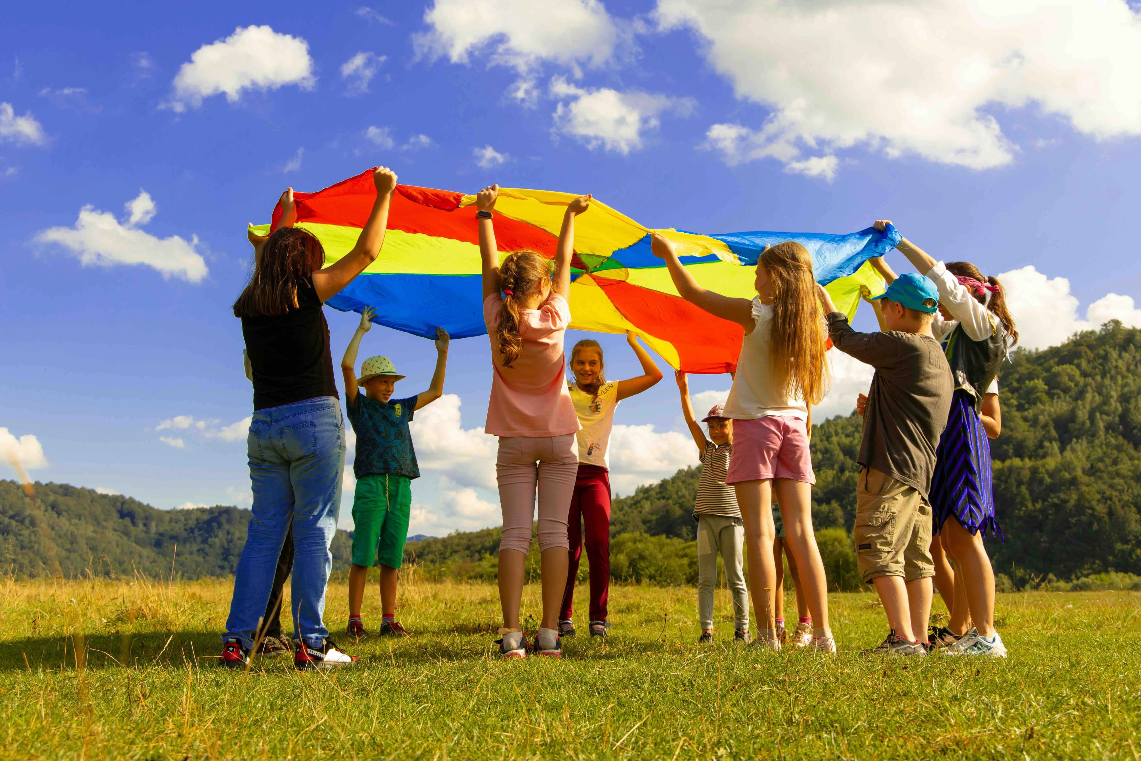 a group of children raise a colorful tapestry