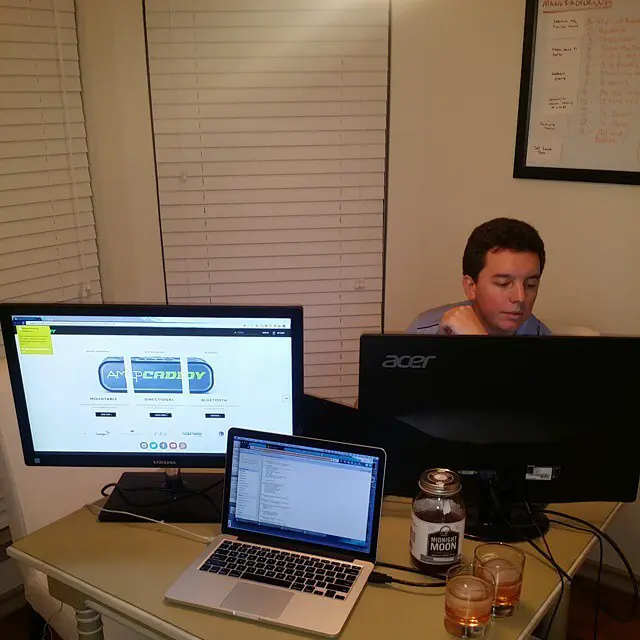 Young man working at a desk with computers showing a golf caddy website