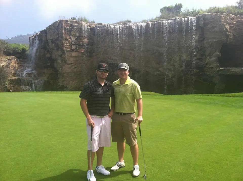 Joe and Garrett on a golf course in front of a rocky waterfall
