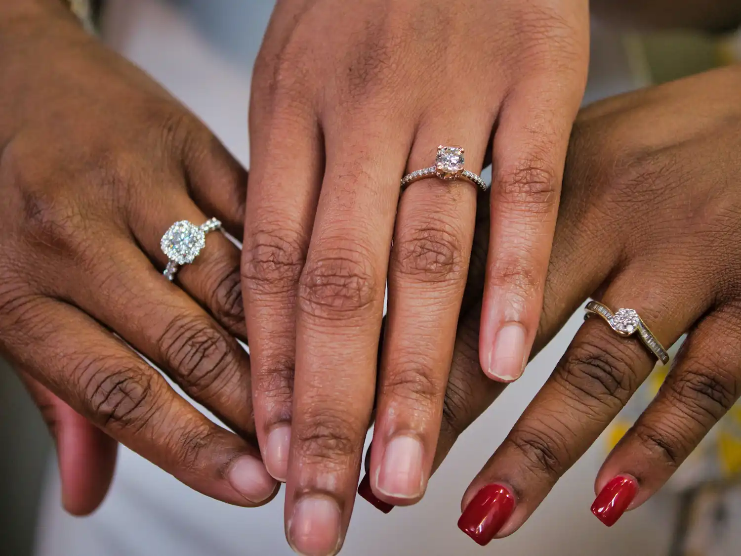 Three hands wearing diamond rings.
