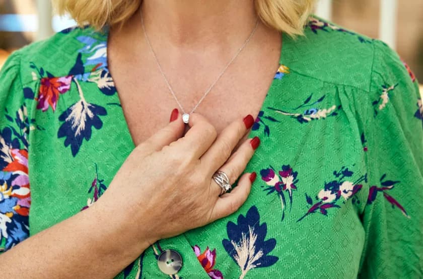 Woman wearing diamond necklace and ring.