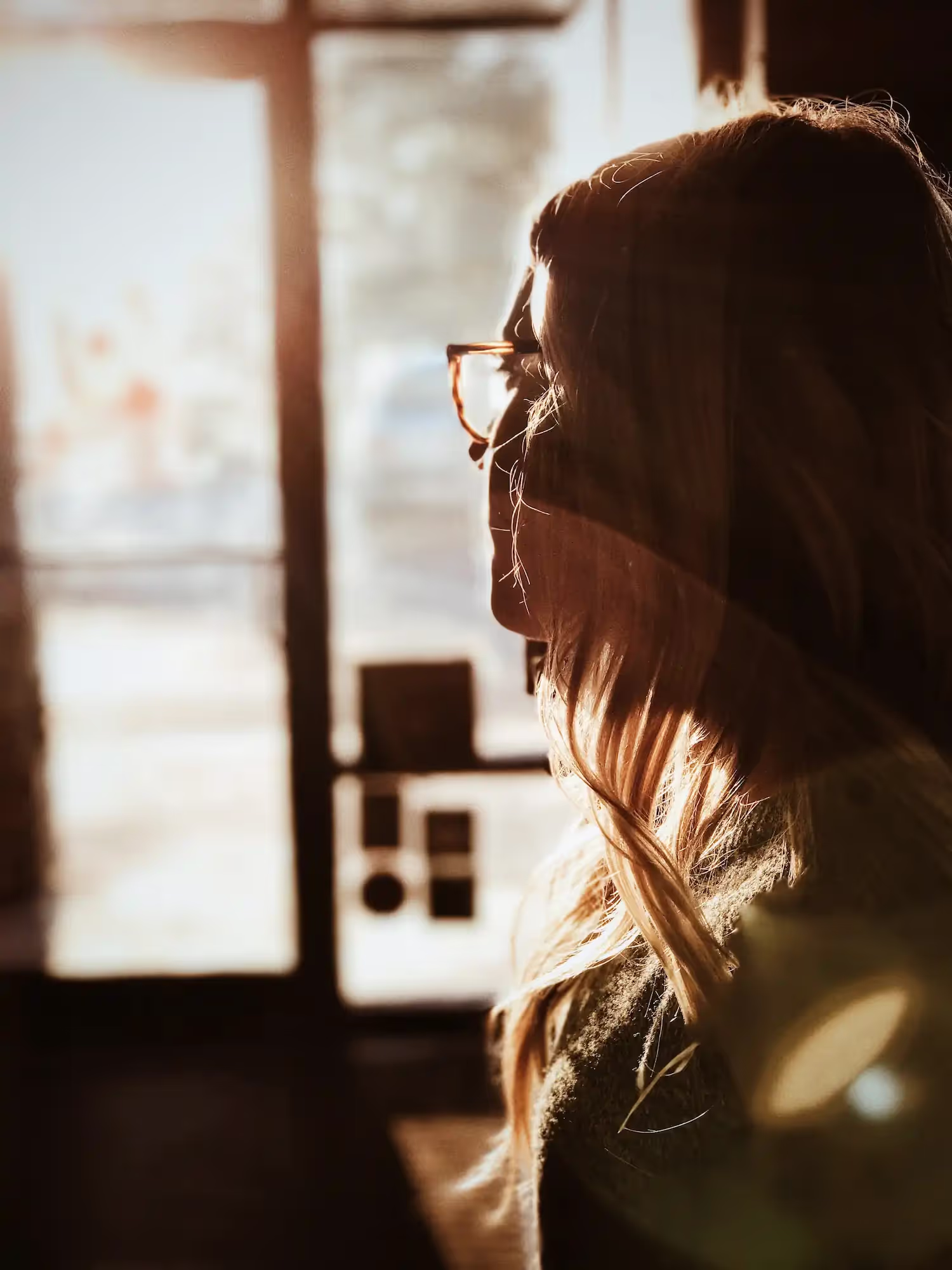 A woman in sunlight looking outside.