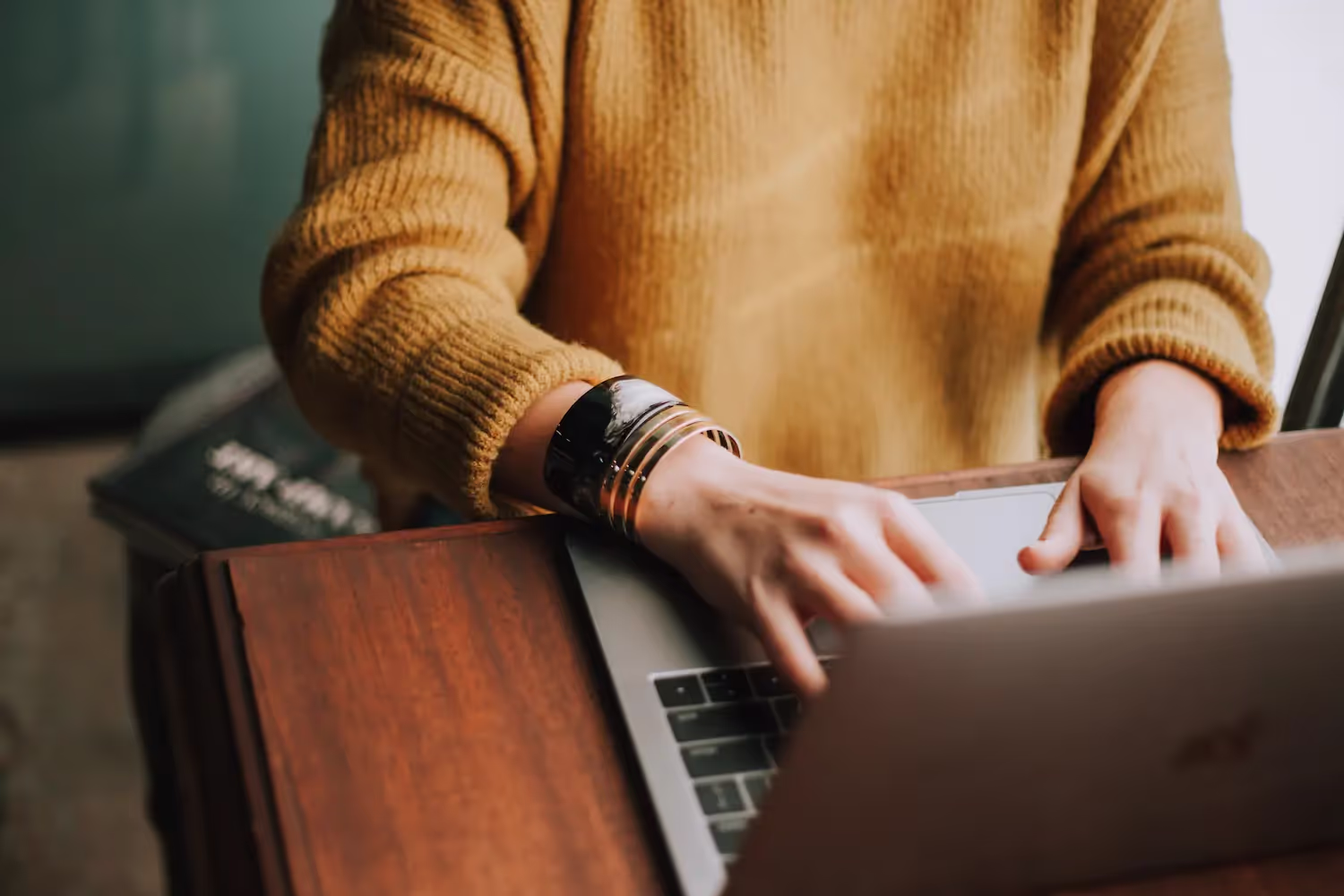 Person wearing bracelets, typing on a computer.