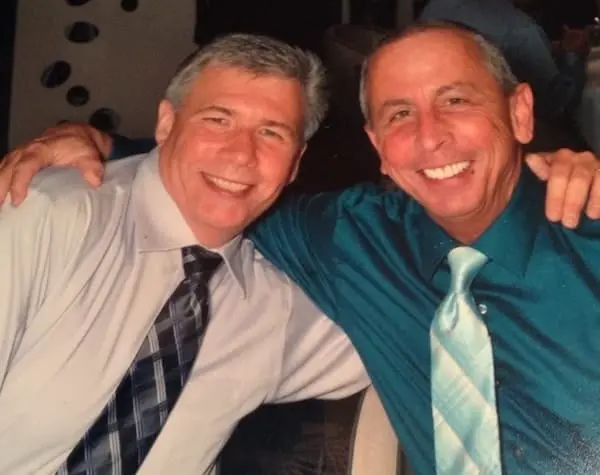Phil and Alan smiling with their arms around each other.