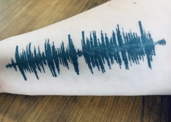 Sound wave tattoo across a forearm, an example of a memorial tattoo.