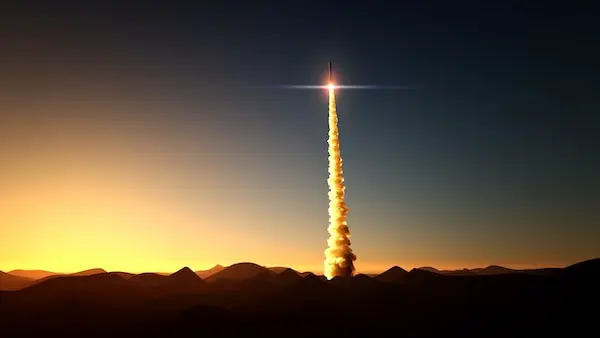 Rocket launching into a twilight sky above a mountain horizon.