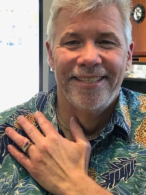 Phil smiling with his hand on his chest, showing the ring set with Alan’s memorial diamond.