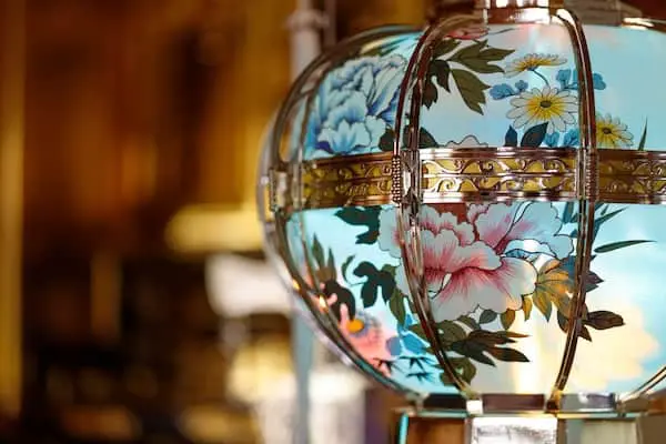 Ornate urn painted with peonies and wrapped in gold metal bands.