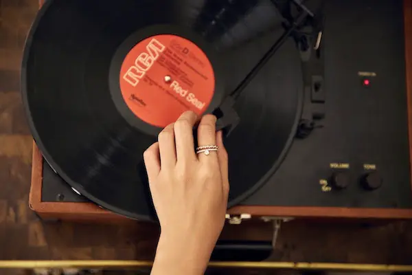 Hand placing the needle on a vinyl record spinning on a turntable.