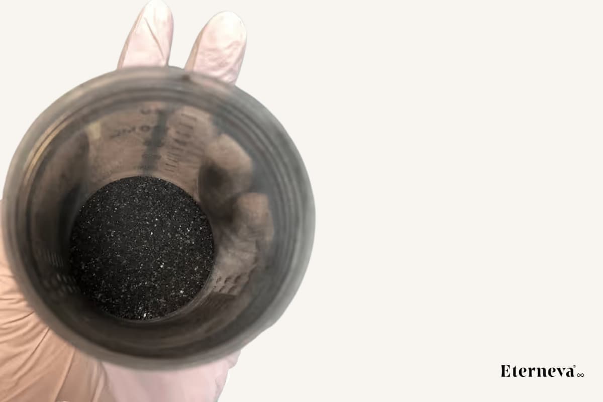 Gloved hand holding a container filled with purified carbon, the material used to grow memorial diamonds.