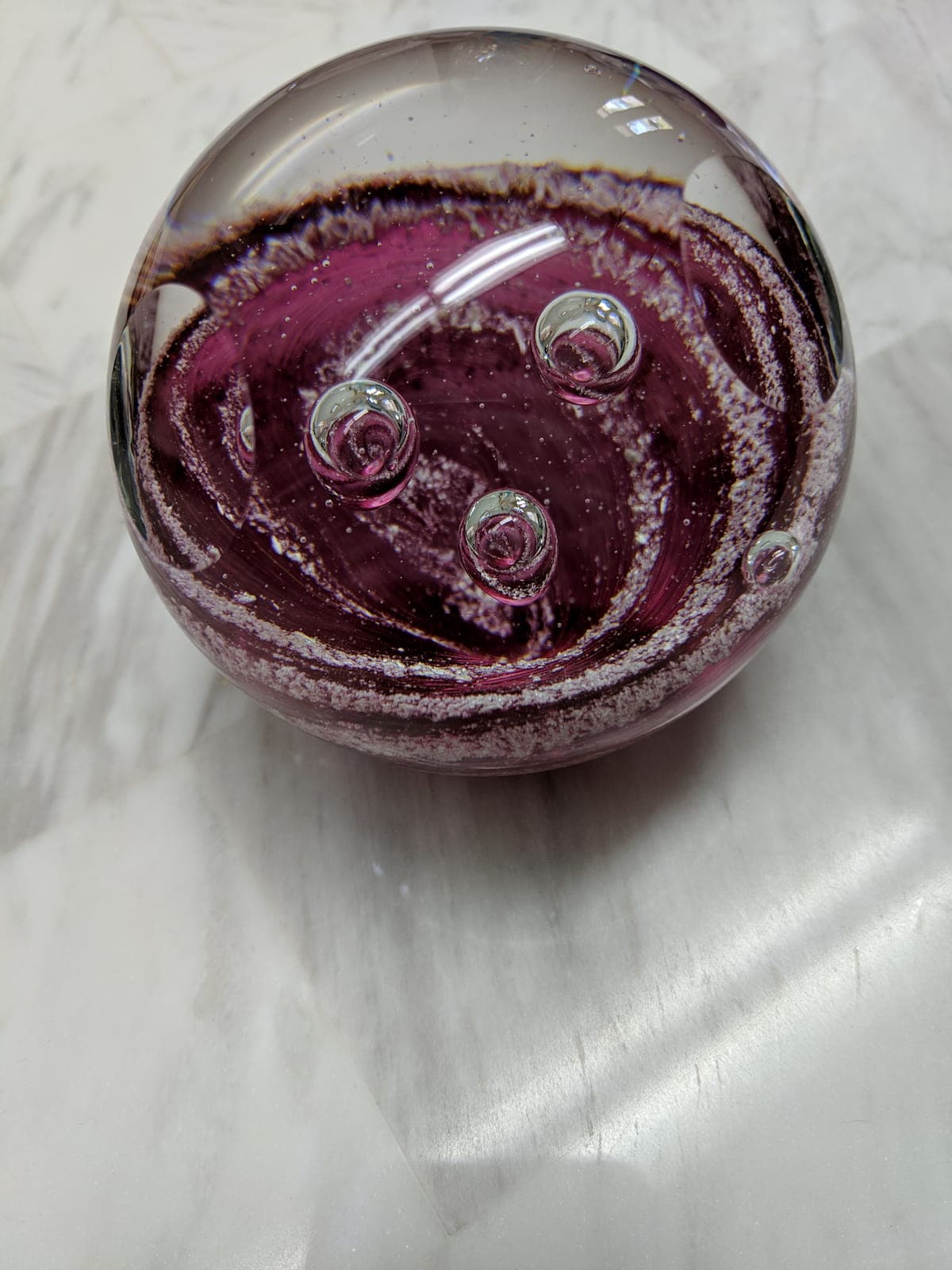 Close-up of a purple memorial glass sphere with swirling patterns and air bubbles, showing how personal carbon is distributed throughout.