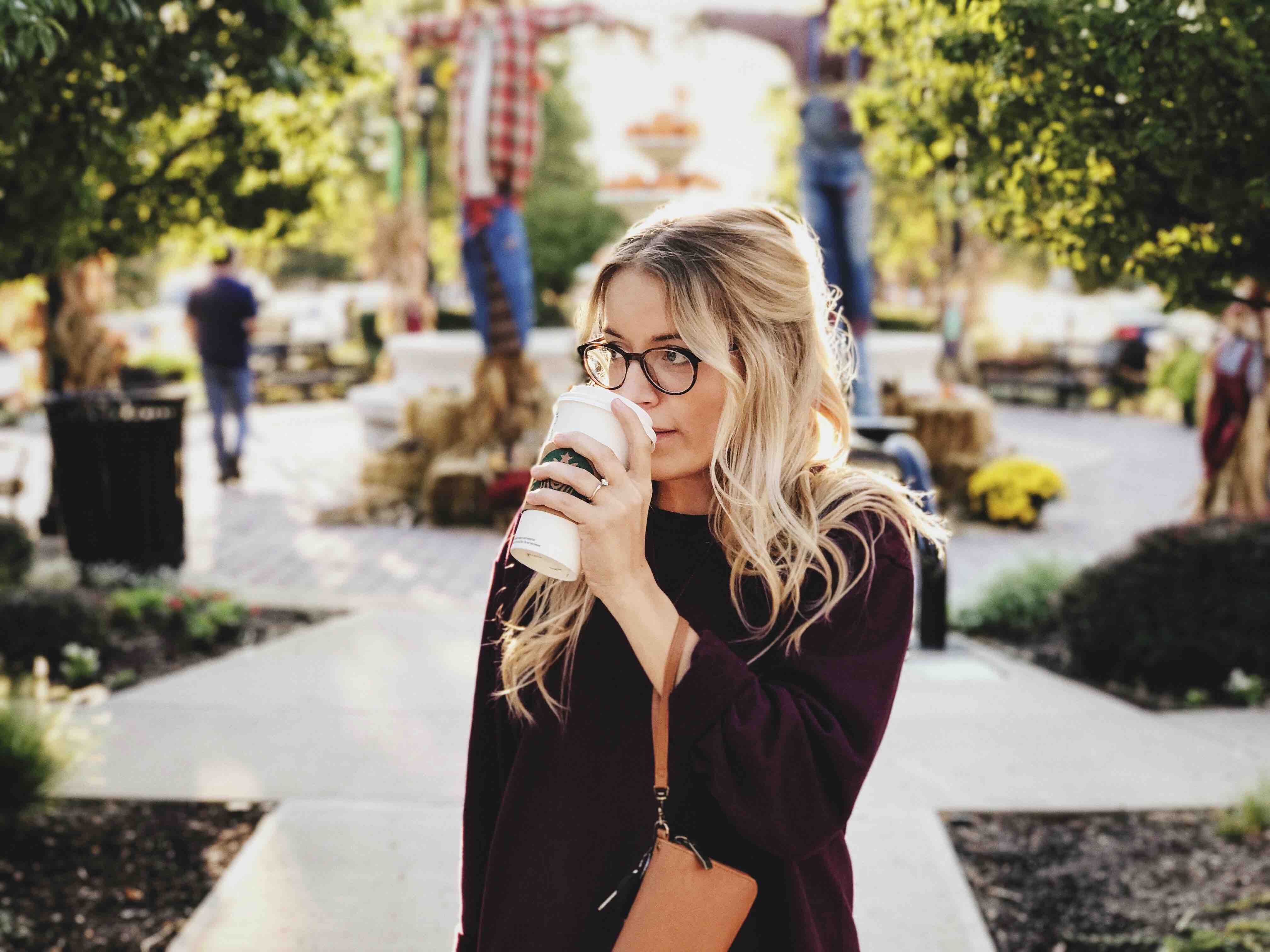 young blonde woman outside drinking coffee
