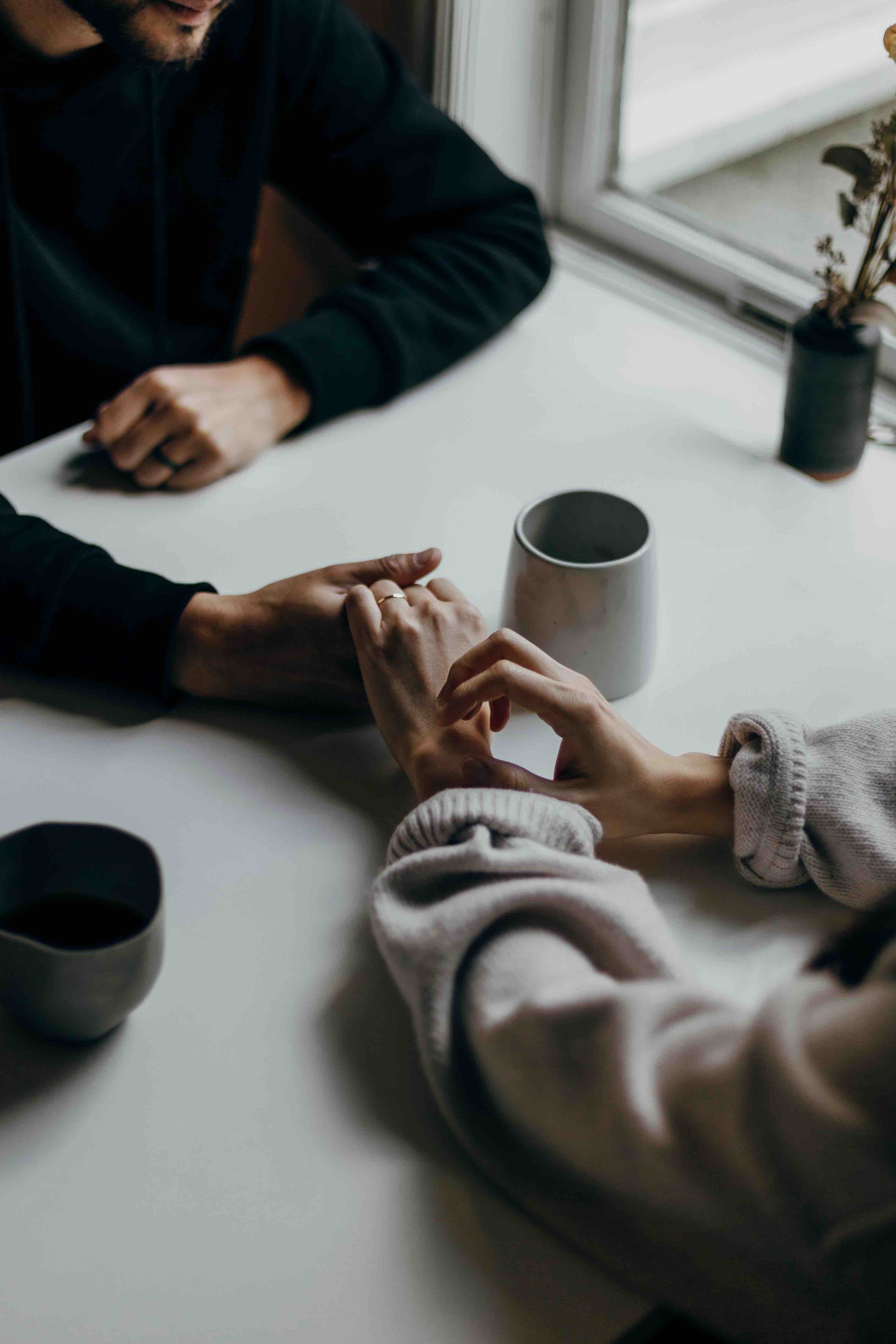 a man and woman hold hands over coffee