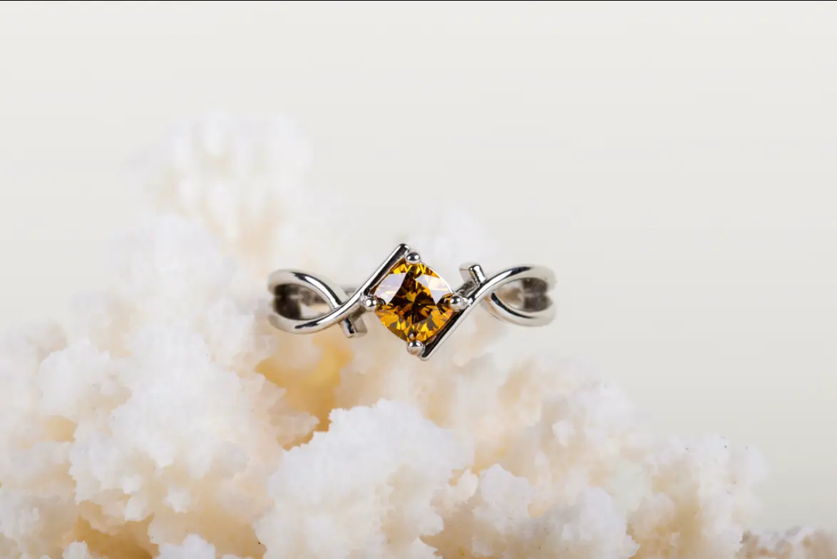 Ring with a yellow-orange diamond in a twisted silver band set on white crystals