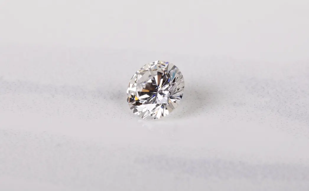 Loose round colorless diamond resting on a white surface