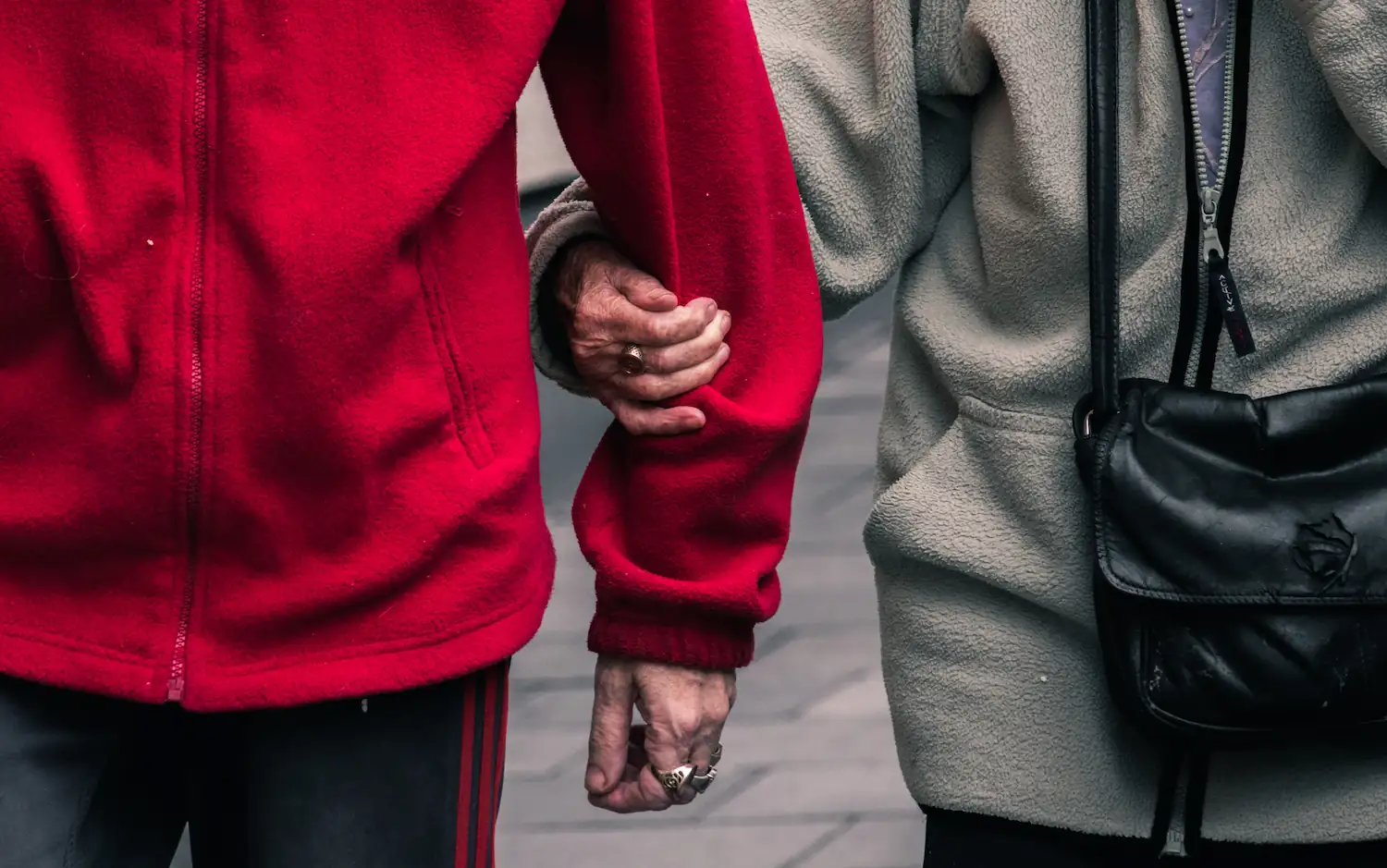 Elderly couple arms linked together, wearing rings.