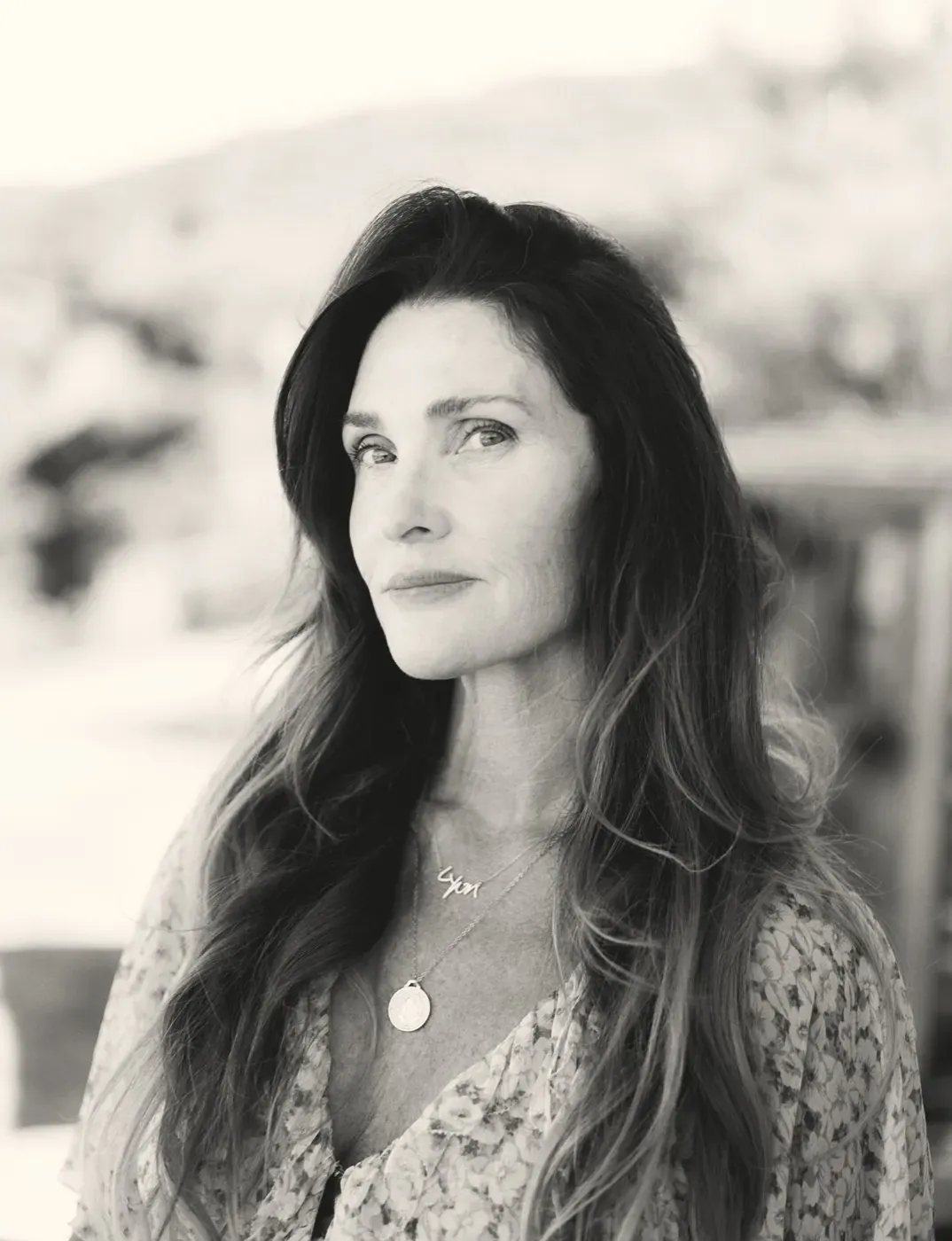 Barbie Herron Conkling with long dark hair, looking softly toward the camera outdoors, in a black and white print