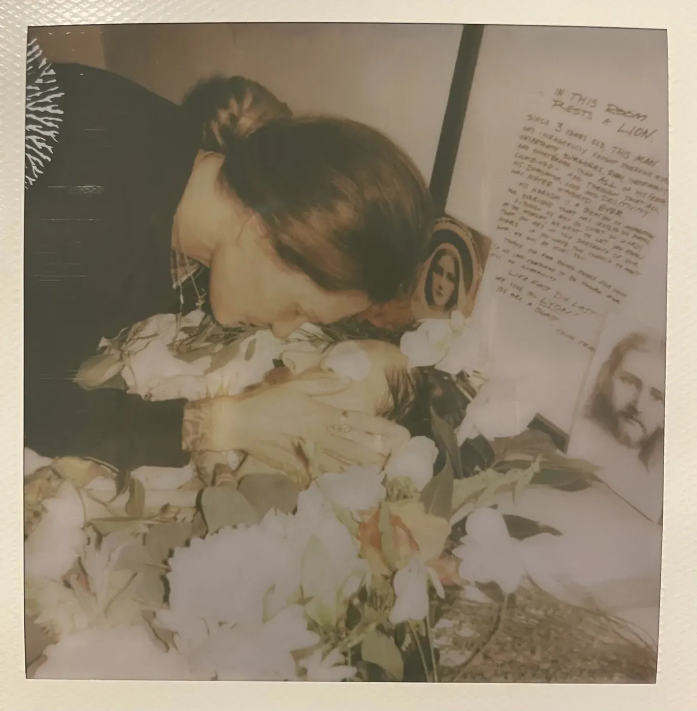 A polaroid of Barbie bowing her head beside her son Lyon among white flowers
